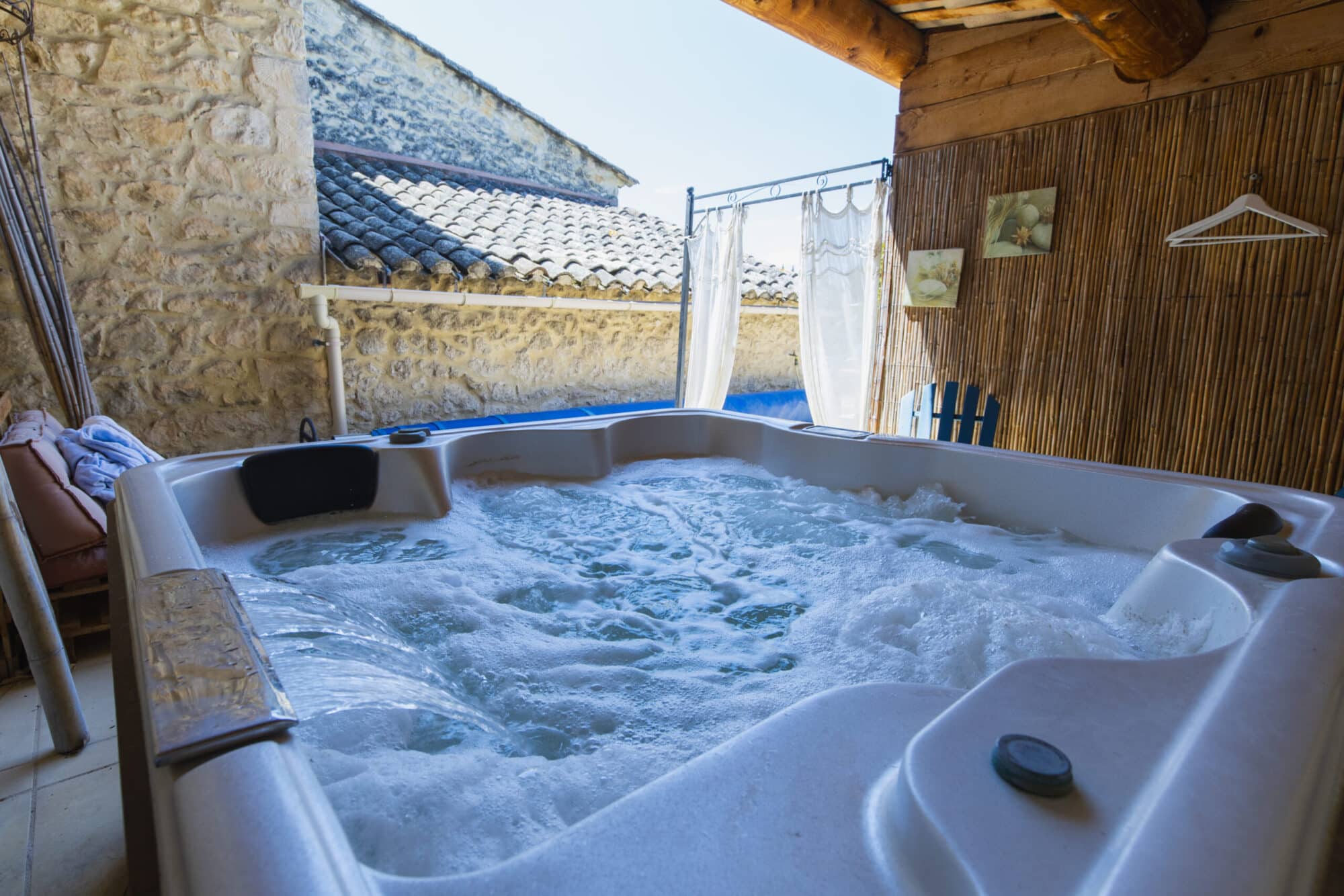 Spa à bulles sur une terrasse en bois avec vue sur les toits et le ciel, en Luberon